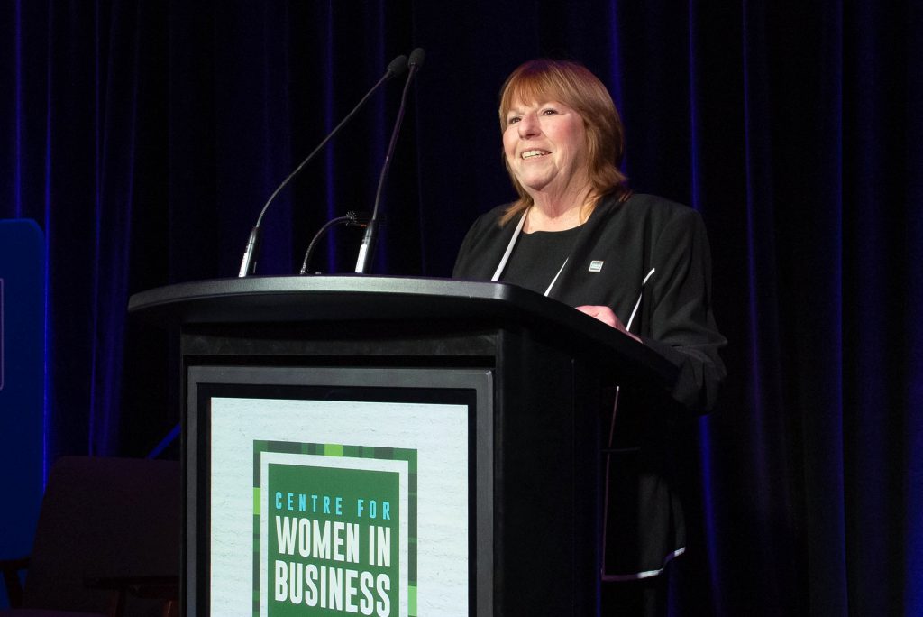 Tanya Priske speaking into a microphone at the CWB International Women's Day event