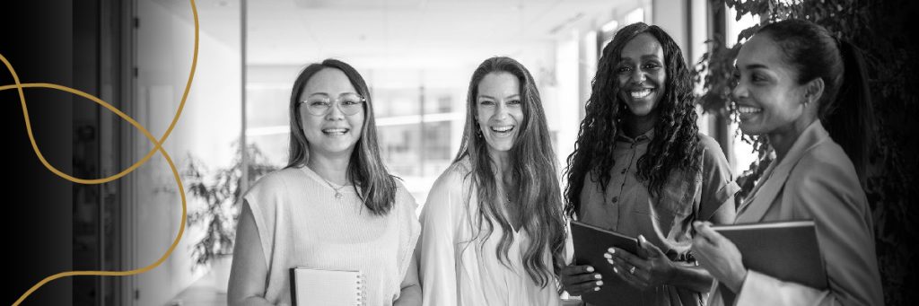 Four women smiling holding note books