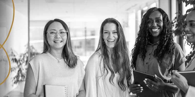 Four women smiling holding note books