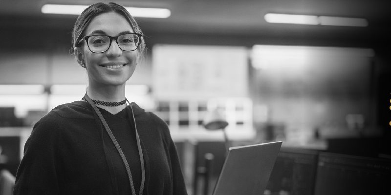 Front profile of a smiling woman wearing eye glasses and lanyard